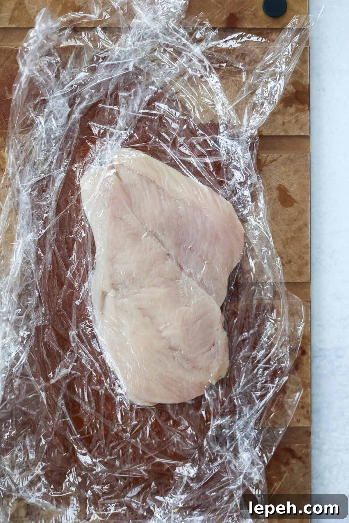 raw chicken breasts wrapped in plastic wrap.