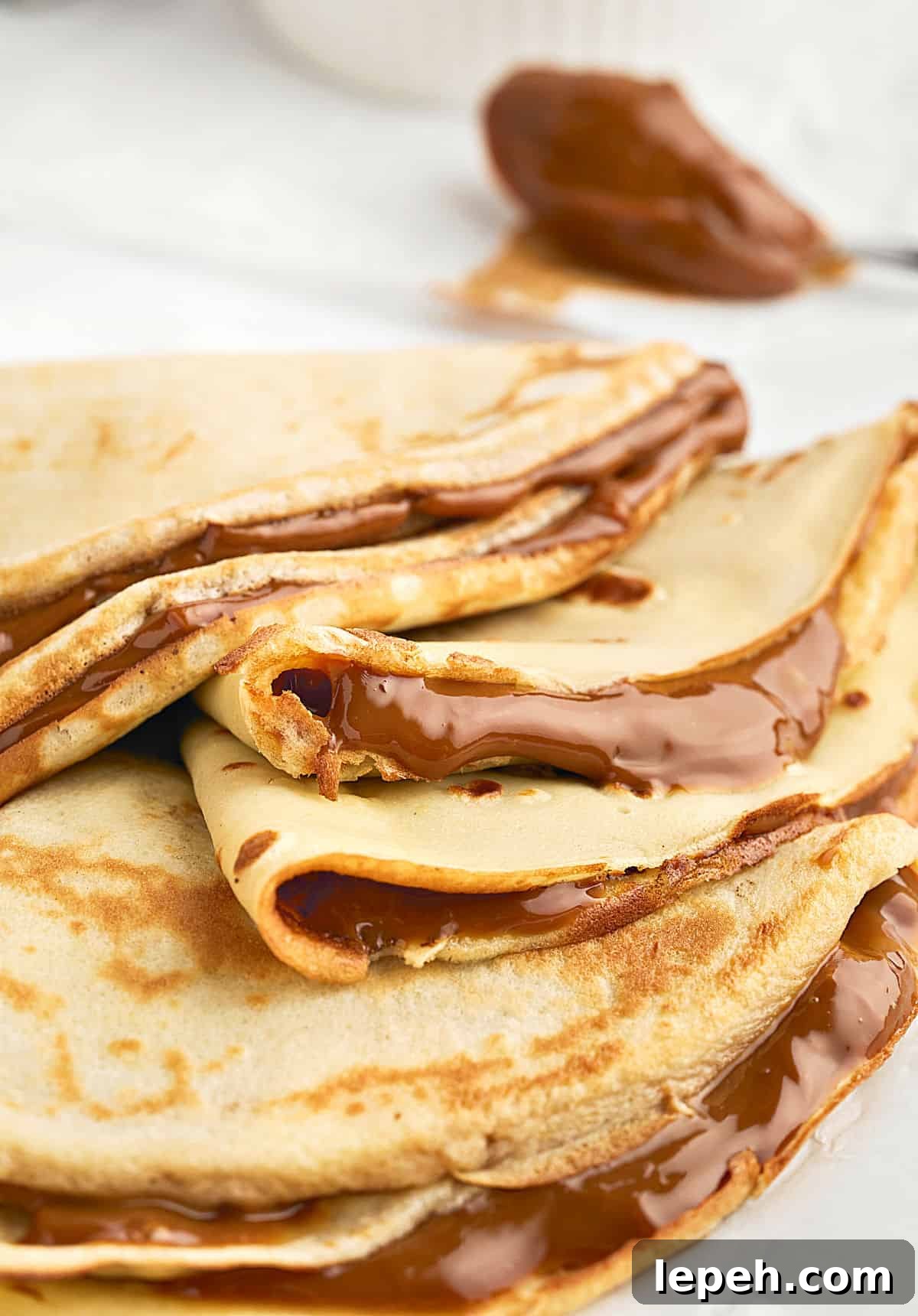 Crepe triangles with dulce de leche on a white plate. Close up view.