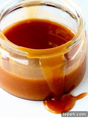 Close up of jar with dulce de leche on a white surface