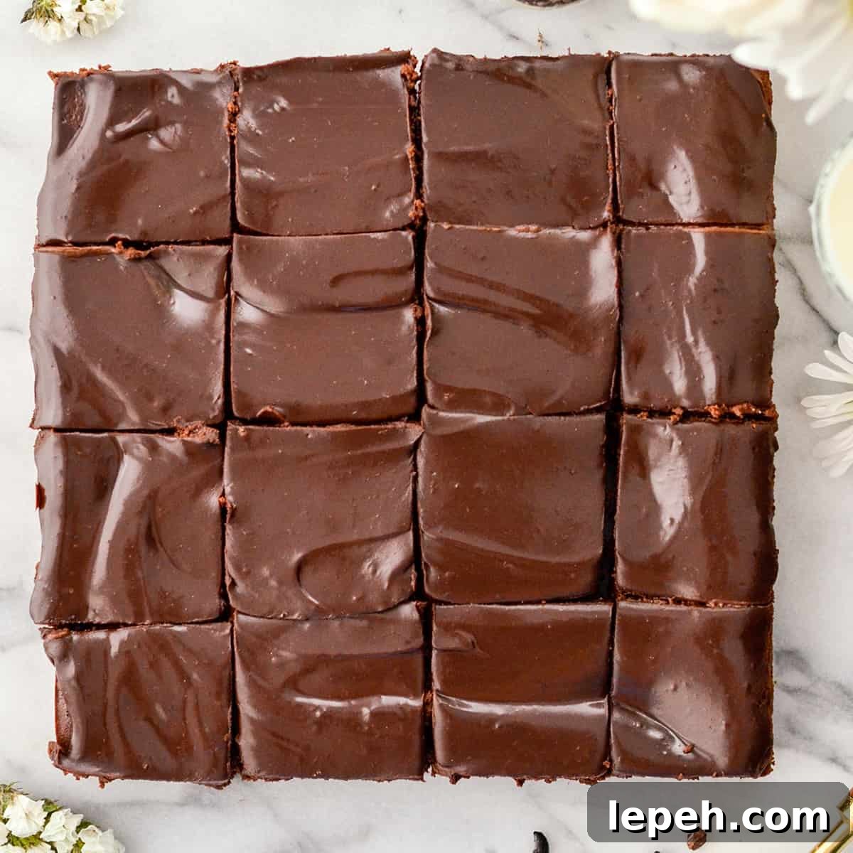 Overhead view of Healthy Greek Yogurt brownies cut into 16 square pieces. A shiny chocolate ganache with swirls. 