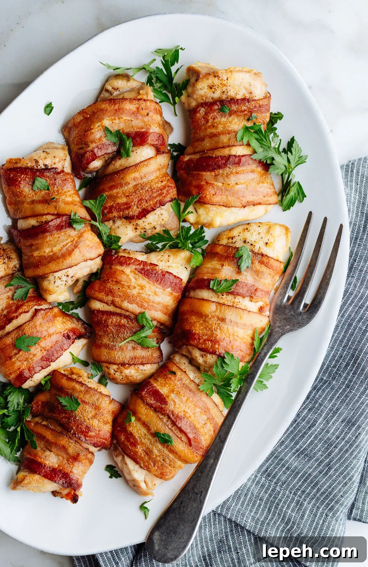 Bacon Wrapped Chicken Thighs served on a white oval platter photographed from above.