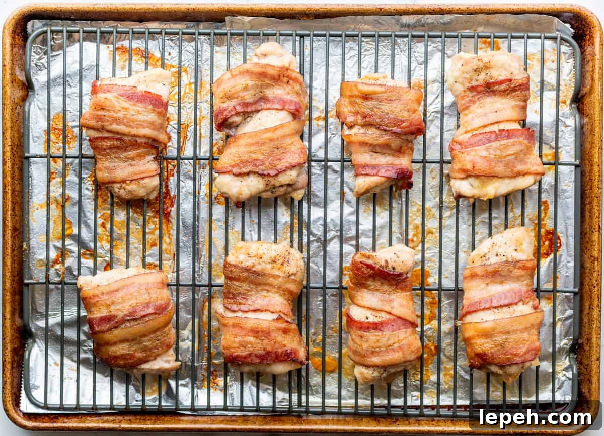 chicken thighs wrapped in bacon on wire rack after baking.
