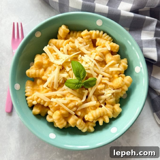 Butternut Squash Pasta served in a small turquoise pasta bowl with white polka dots, and garnished with  a sprig of basil.