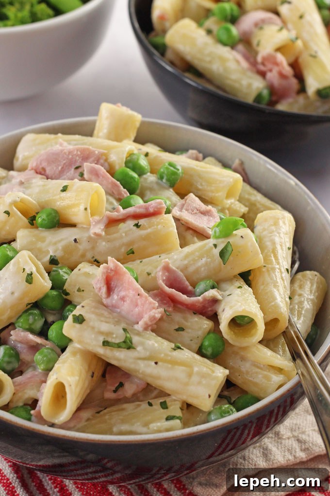 A close up shot of the Creamy Ham & Pea Pasta in a bowl with a fork in it.