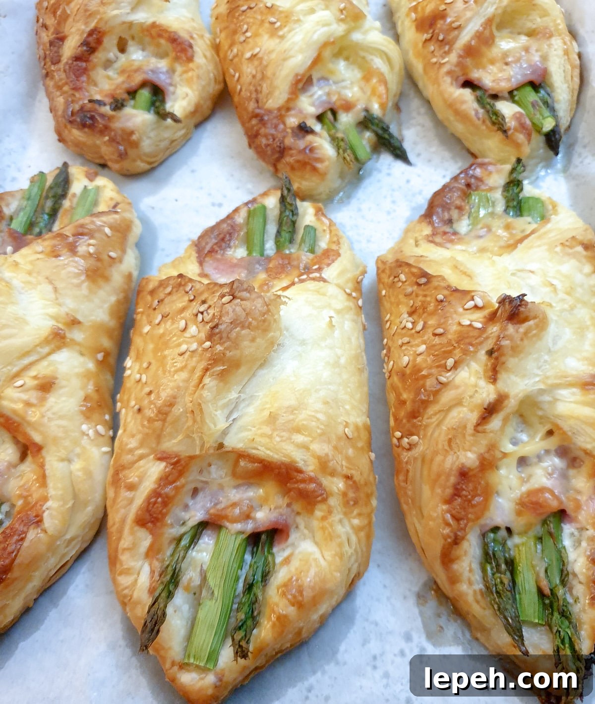 6 puff pastry asparagus and ham wraps on a plate.