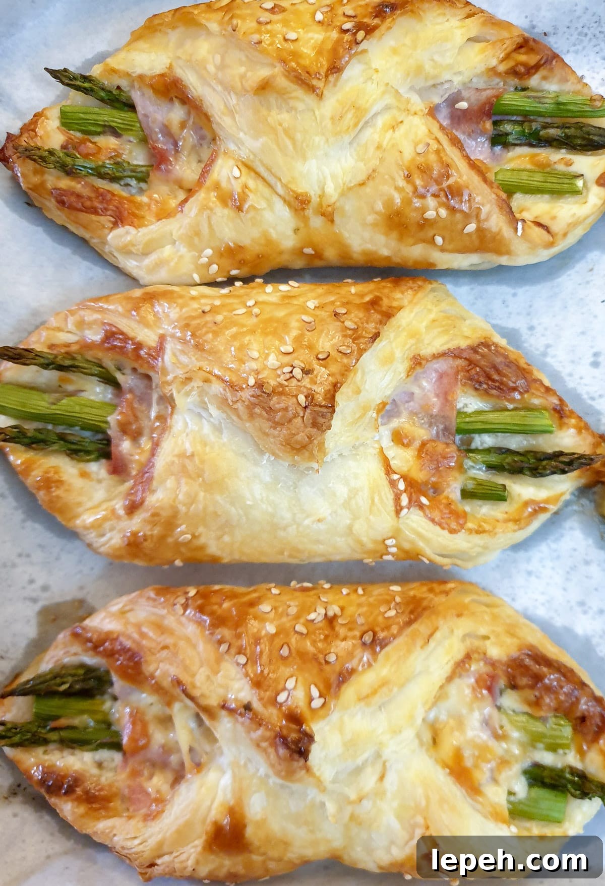 Overhead shot of 3 baked ham and asparagus bundles.