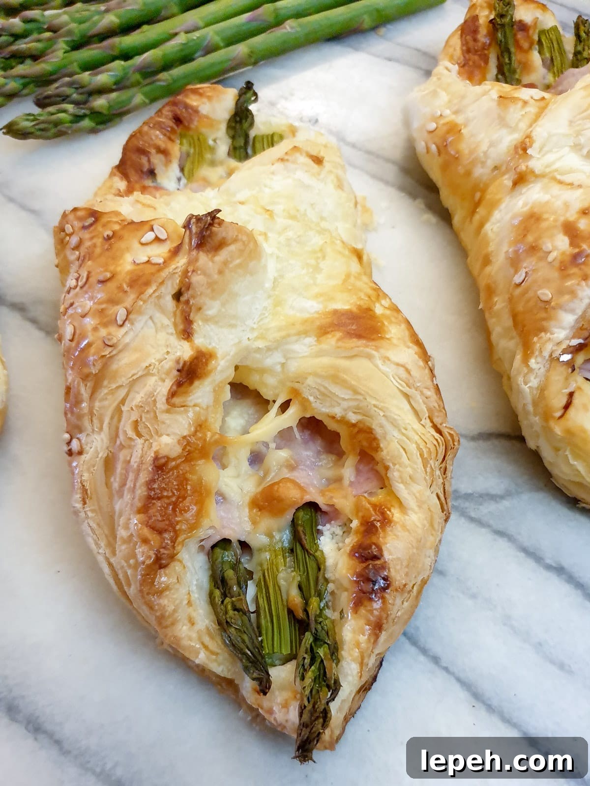 Close up of asparagus and ham wrapped in lightly browned puff pastry.