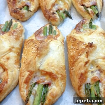 6 puff pastry asparagus and ham wraps on a plate.