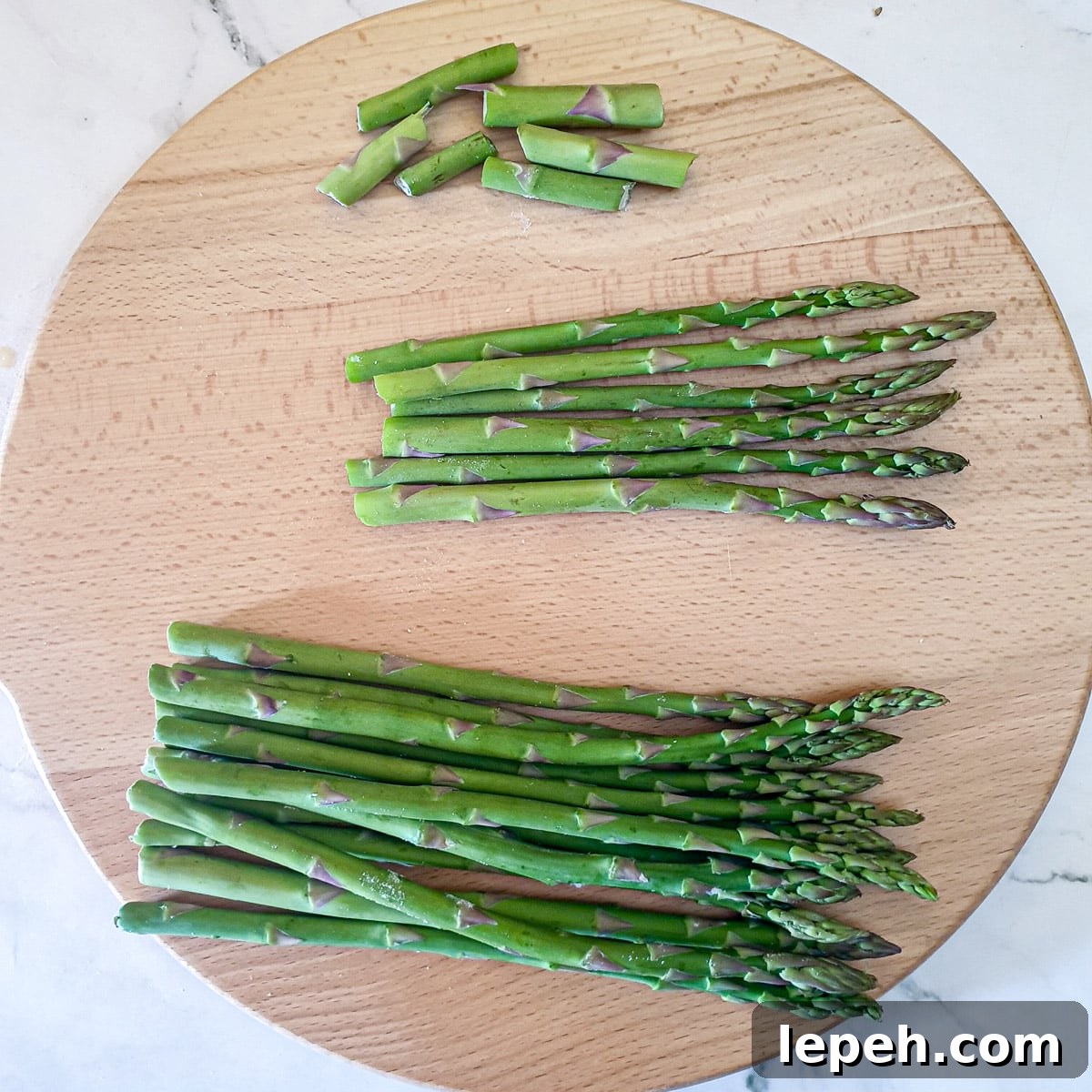 Asparagus spears on a wooden board showing the ends snapped off.
