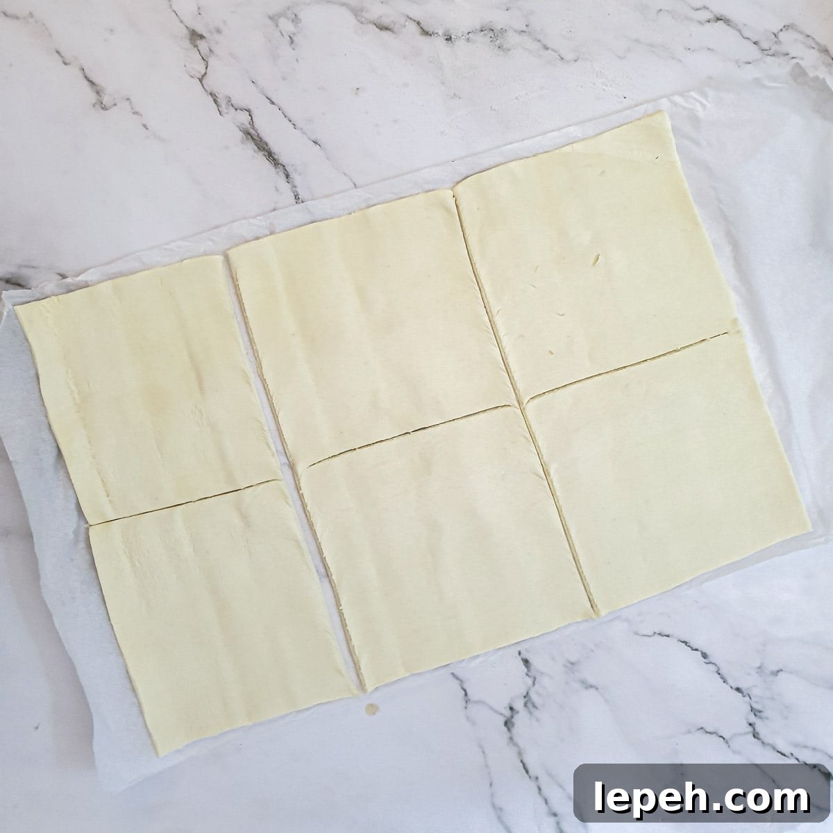 A sheet of puff pastry cut into 6 squares.