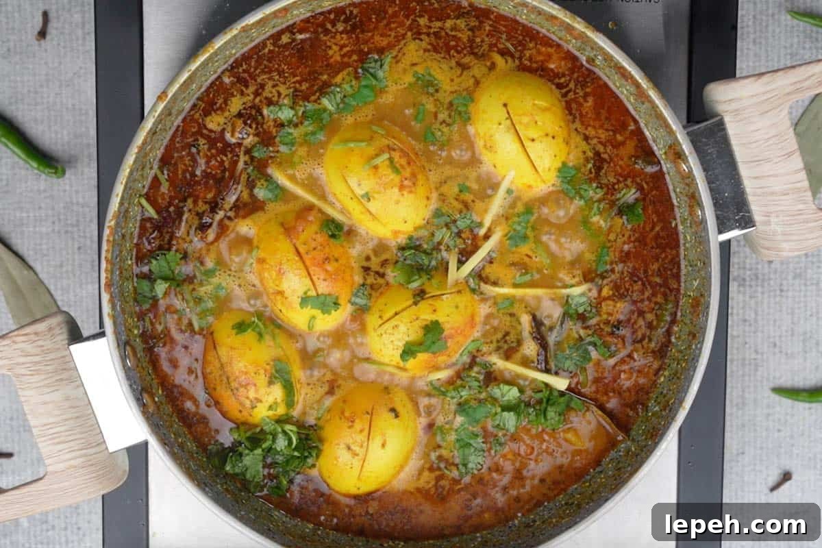 Ready dhaba egg curry garnished with cilantro and ginger juliennes.