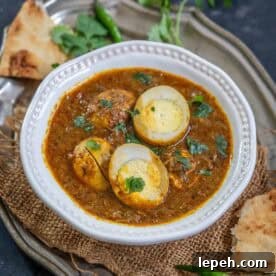 A white bowl of Dhaba Style Egg Curry garnished with cilantro.