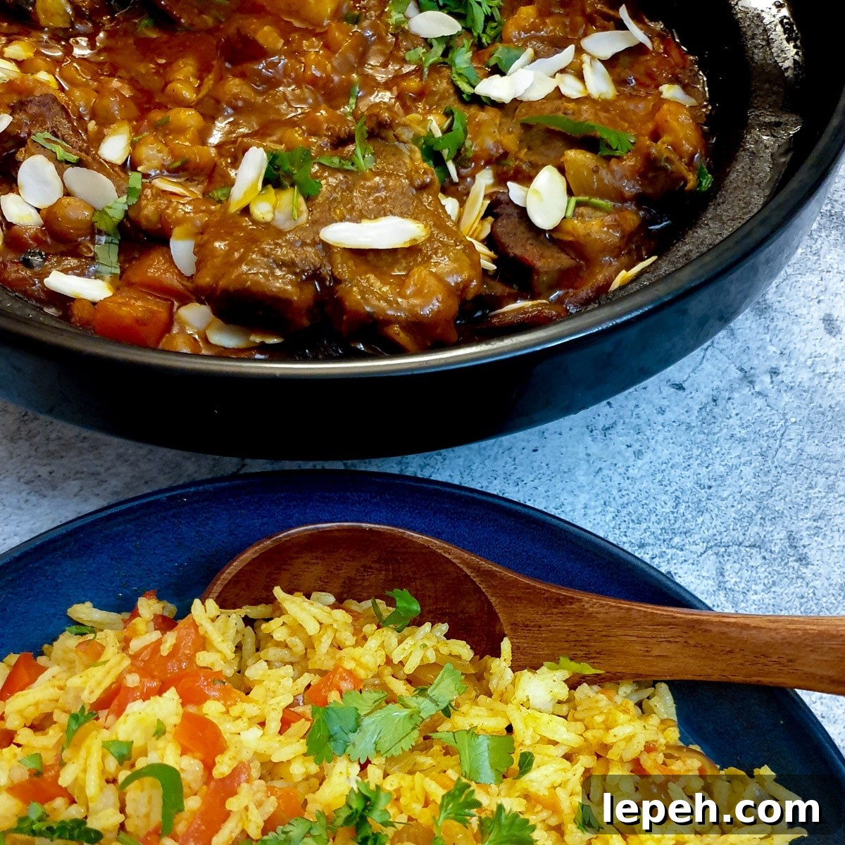 A tagine filled with Moroccan lamb stew next to a bowl of spicy rice.