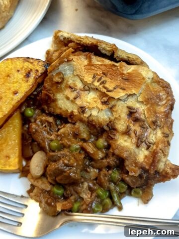 A slice of Moroccan lamb pie on a white plate with two slices of roasted butternut squash.