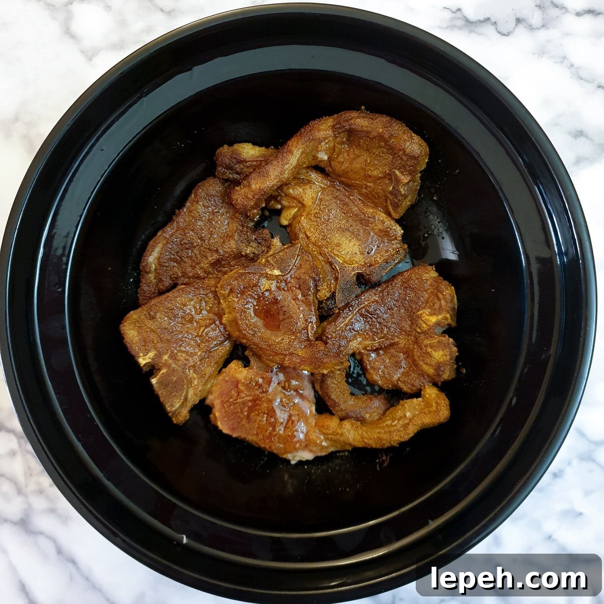 Browned lamb chops arranged in the base of a tagine.