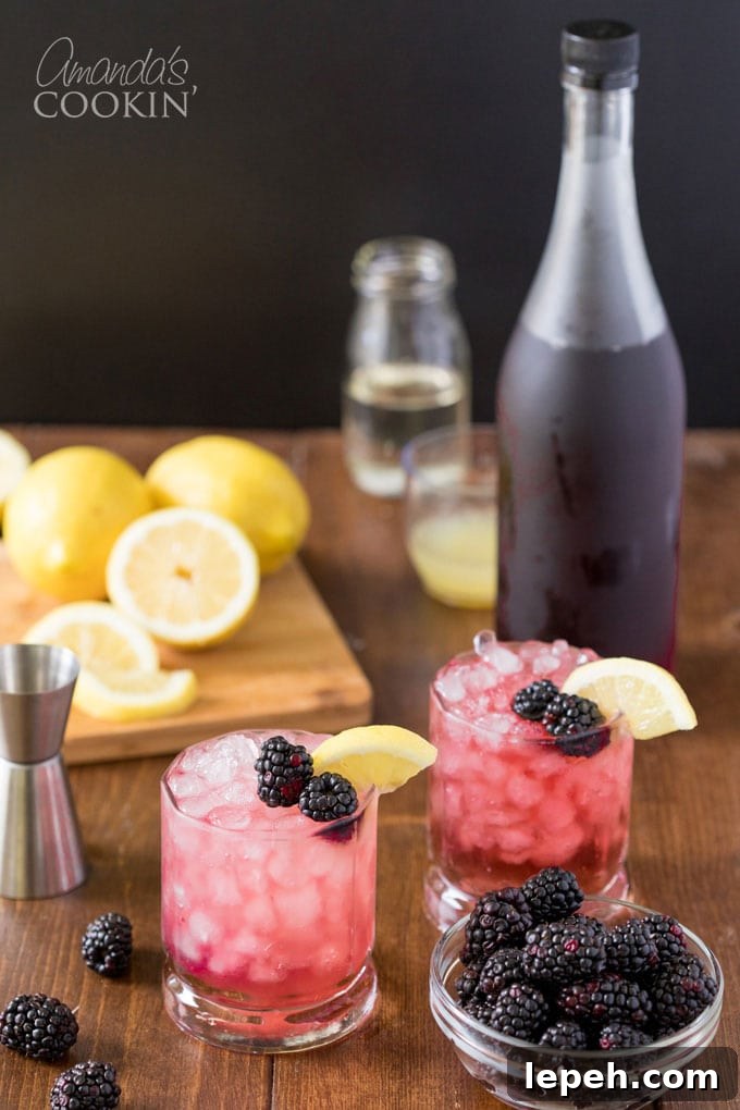 two bramble cocktails with blackberry liqueur bottle in background