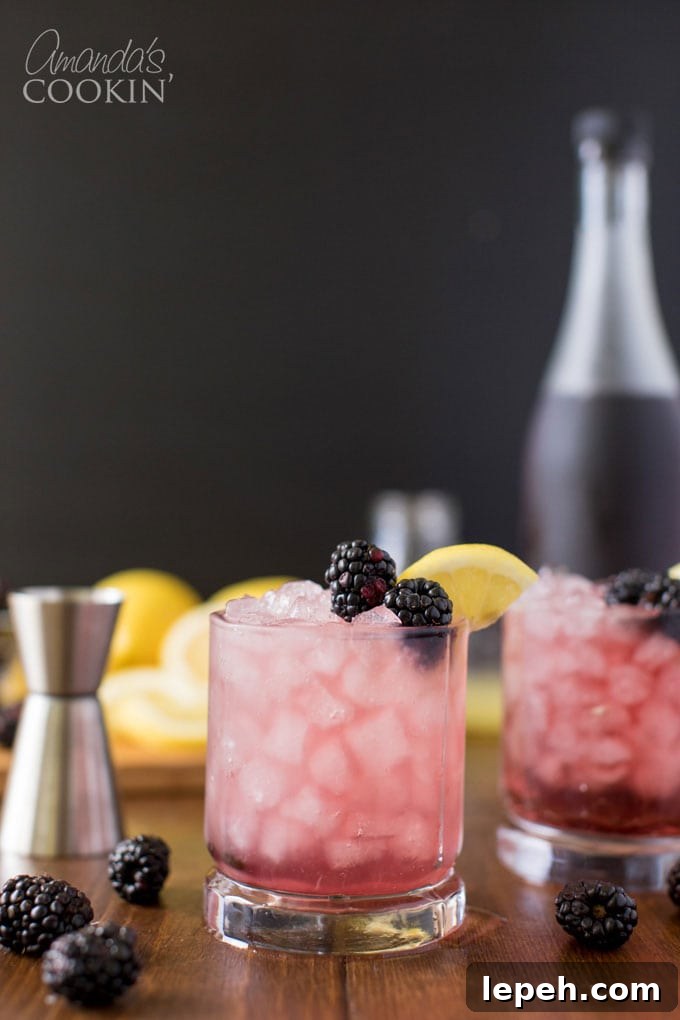 glass of bramble cocktail with blackberry and lemon garnish