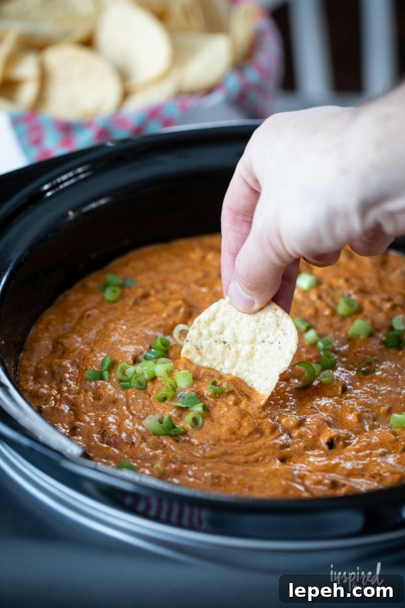 dipping a chip into Hot Chili Cheese Dip