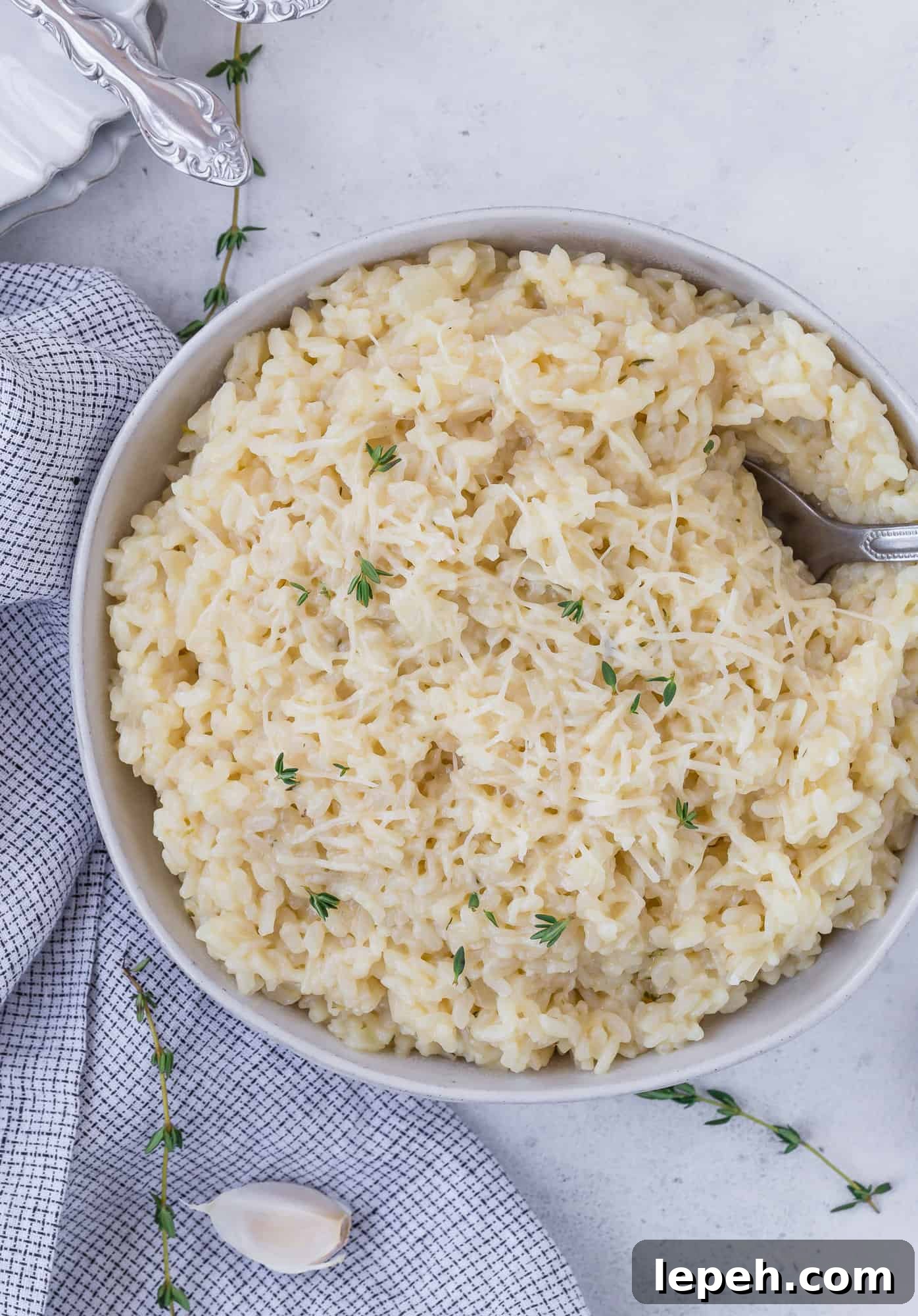 Bowl of instant pot risotto topped with parmesan cheese and fresh thyme.