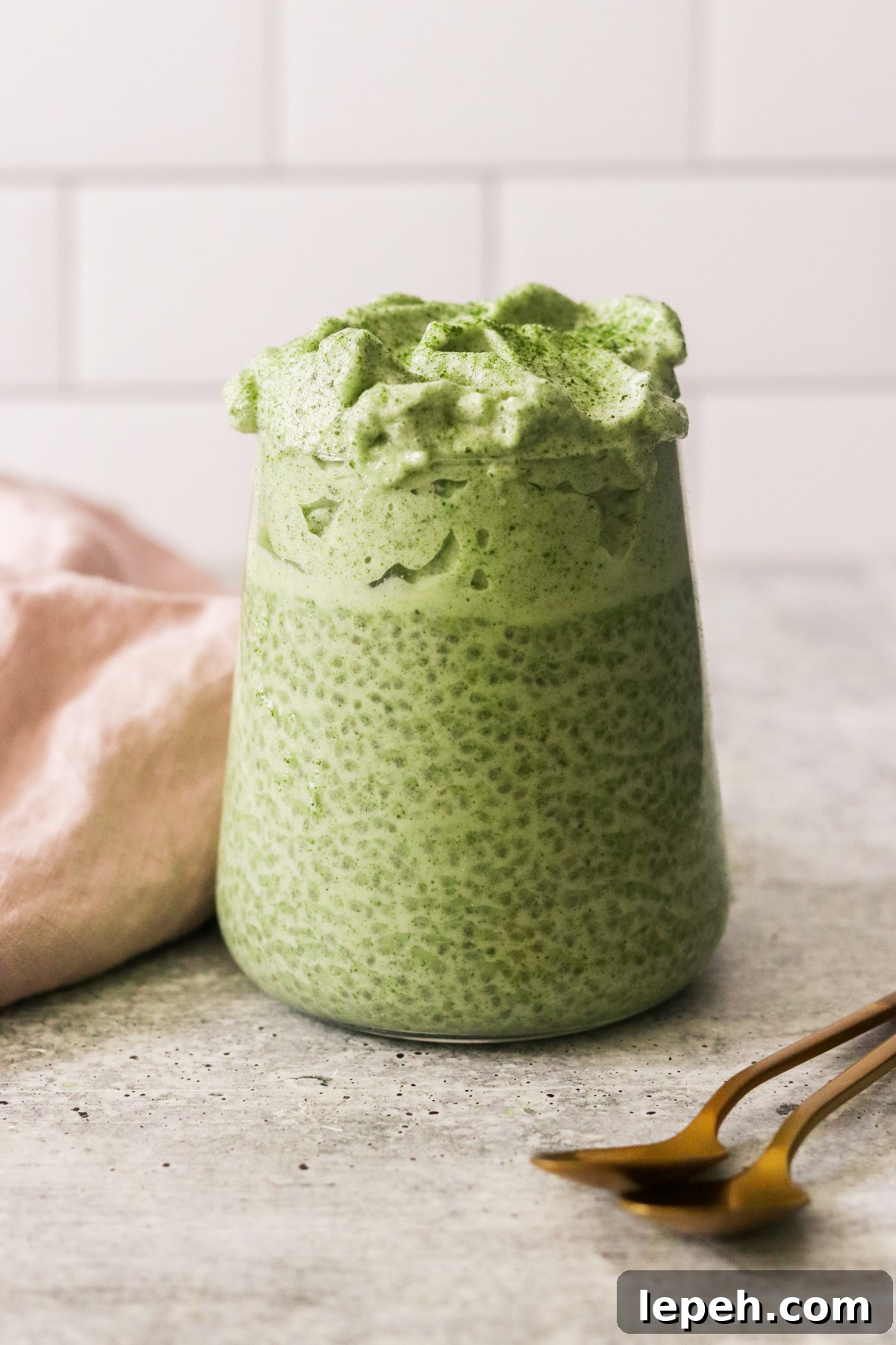 a glass jar filled with matcha chia pudding and topped with dalgona.