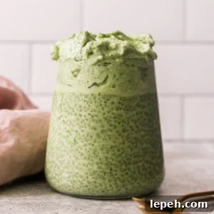 a glass jar filled with matcha chia pudding and topped with dalgona.
