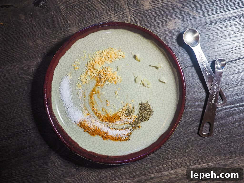 Spices and two measuring spoons on a gray wooden background.