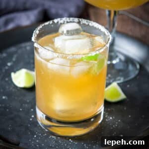 A salted glass with a margarita in it on a metal tray with lime wedges - square