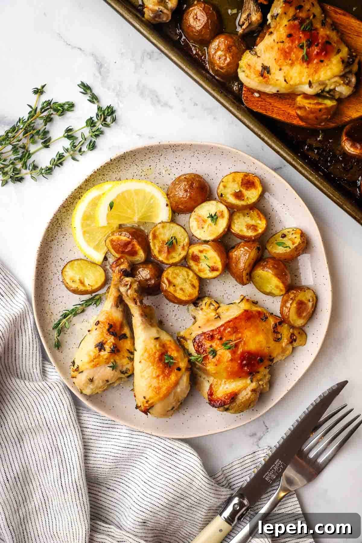 Roasted chicken parts and potatoes on a plate with lemon slices.