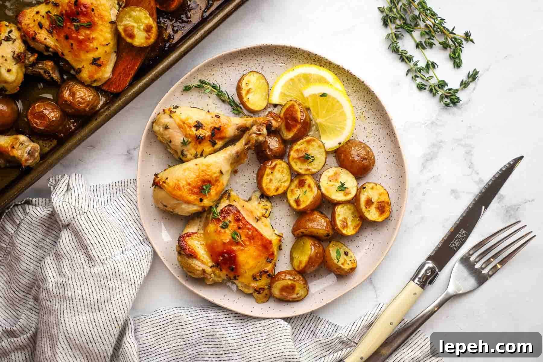 Roasted chicken parts and potatoes on a plate with lemon slices.