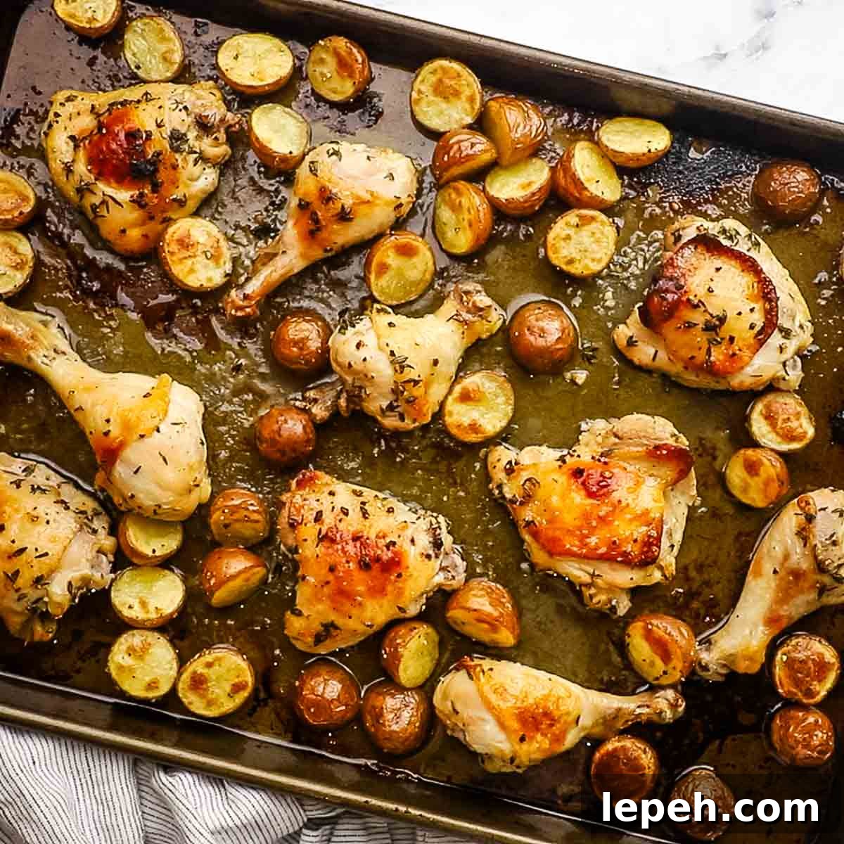 golden brown baked chicken parts with potatoes on a baking sheet