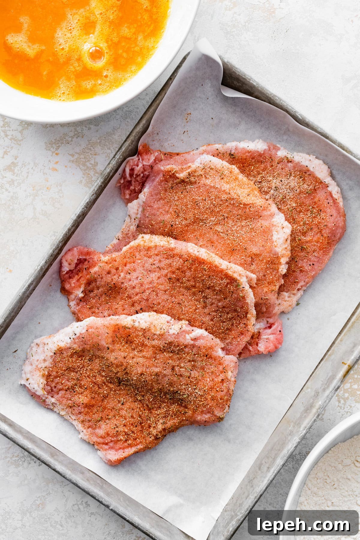 Seasoned pork chops on a tray.