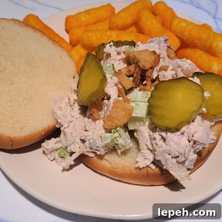 Smoked Turkey Salad on a bun on a plate served with cheese puffs