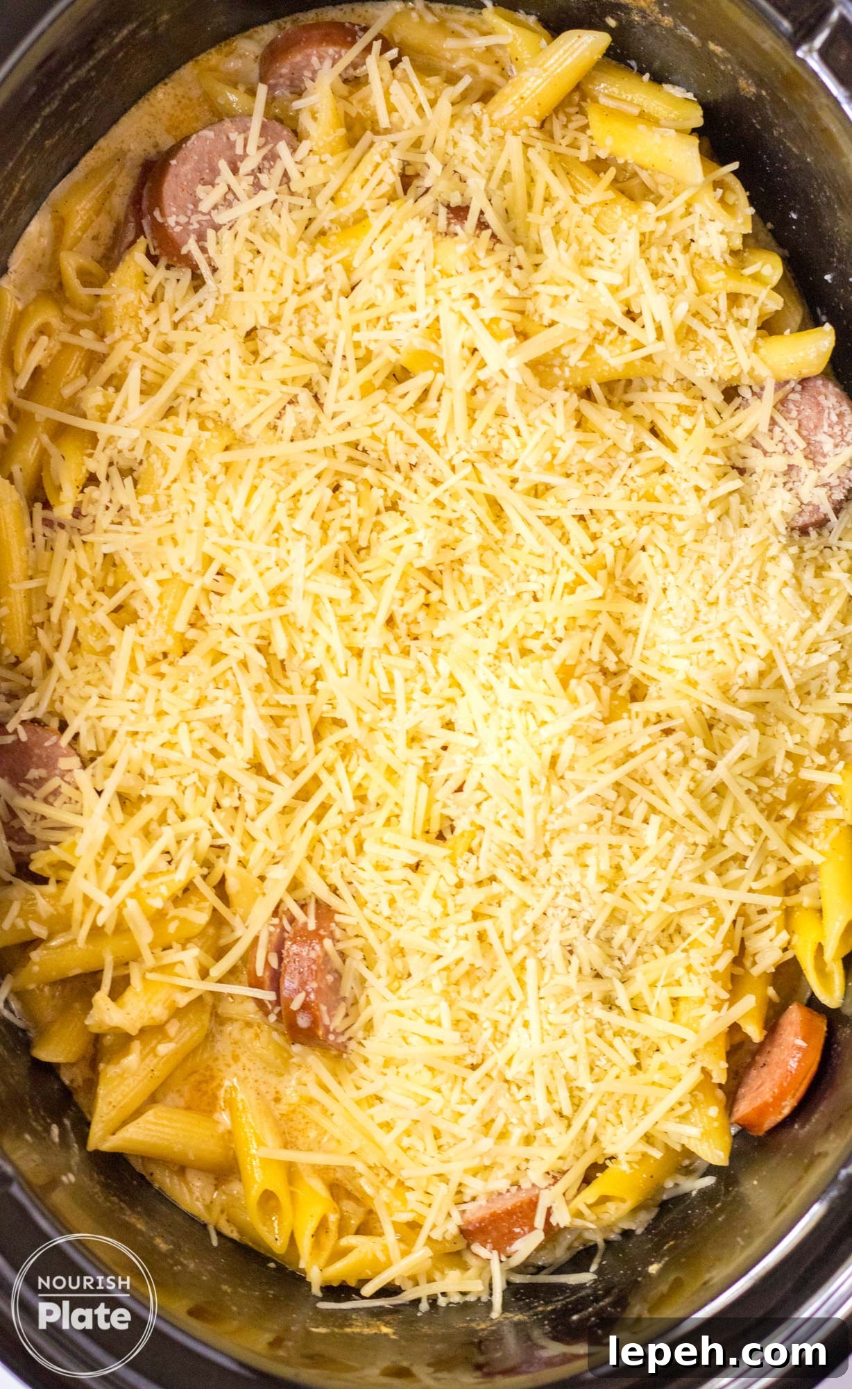 Cajun chicken alfredo in a slow cooker covered with shredded cheese