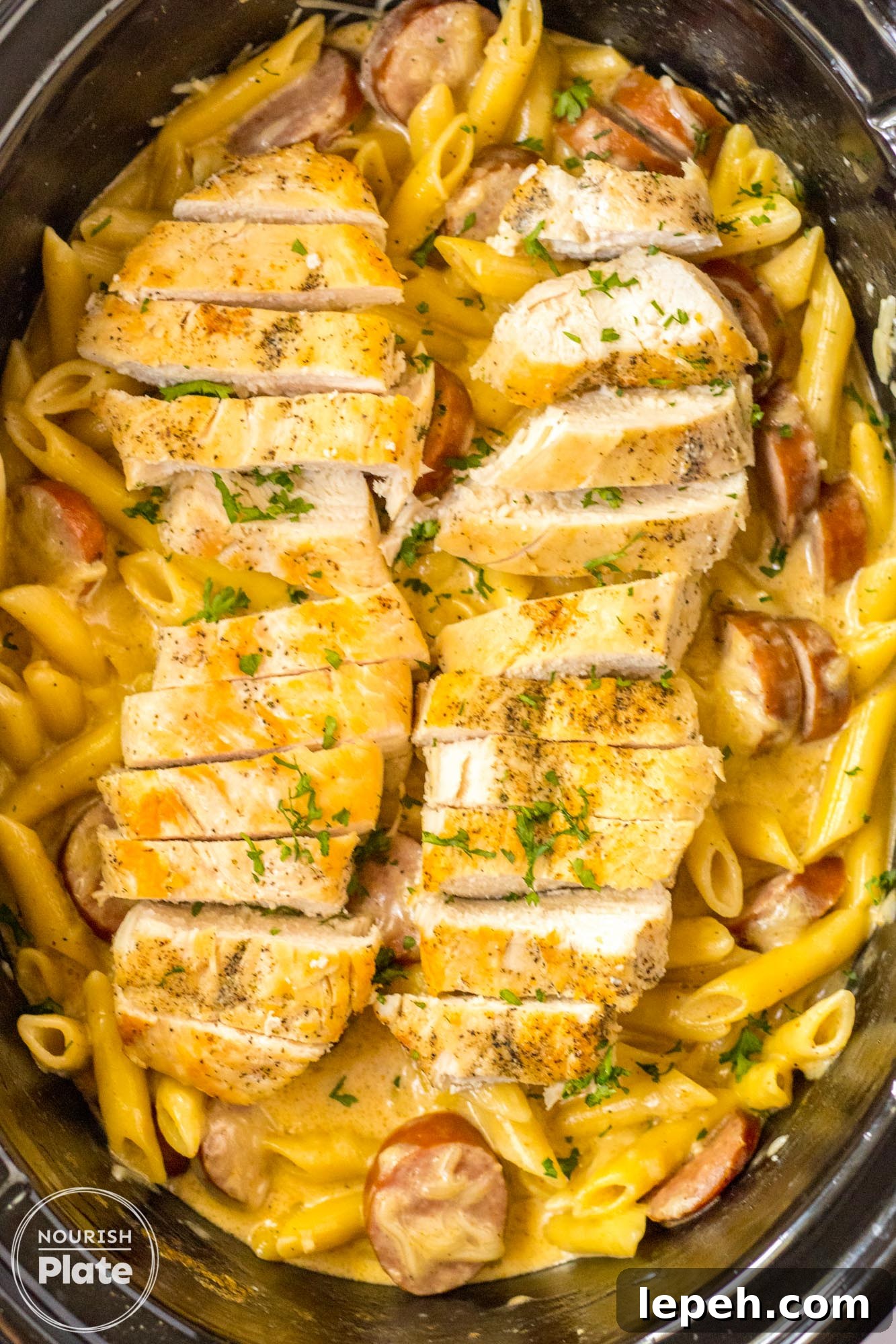 Overhead shot of cajun alfredo with sliced chicken in a slow cooker