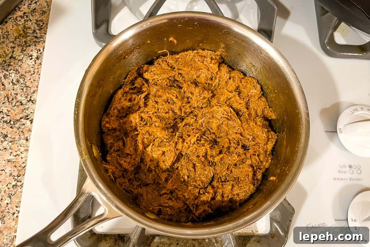 Saucepan on stove with reheated and seasoned pulled pork