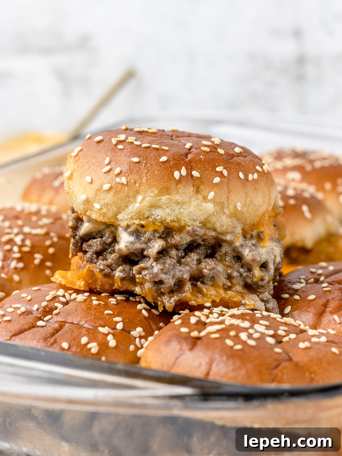 Cheesy Ground Beef Slider with gooey cheese and sriracha aioli sauce squeezing out.