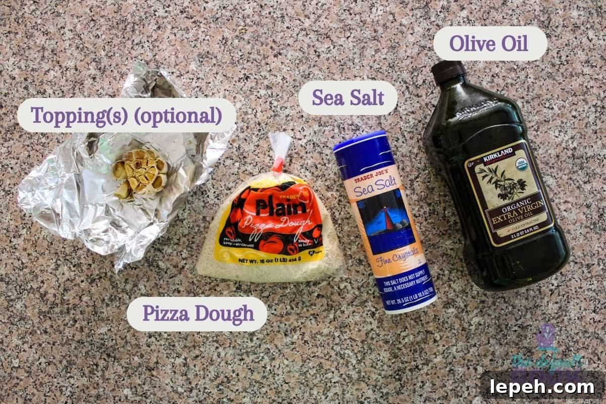 Labeled ingredients sitting on a counter: roasted garlic, pizza dough, sea salt, and olive oil.