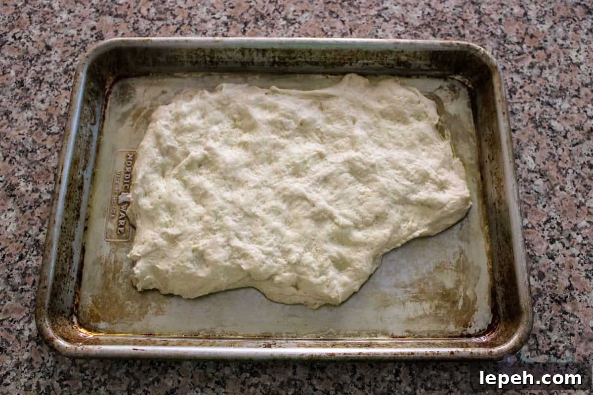 Pizza dough on a greased quarter sheet pan.