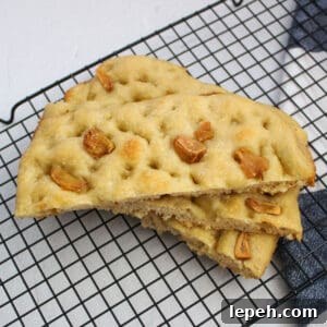 Sliced focaccia bread with roasted garlic topping on a cooling rack.
