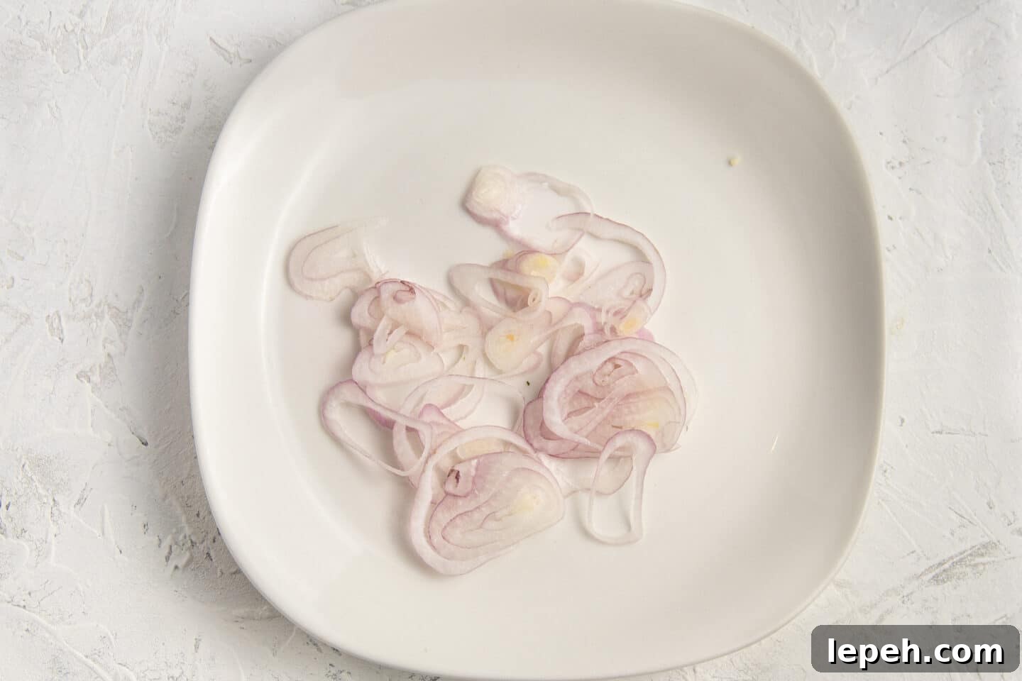 Picture of plate with thinly sliced shallots. 