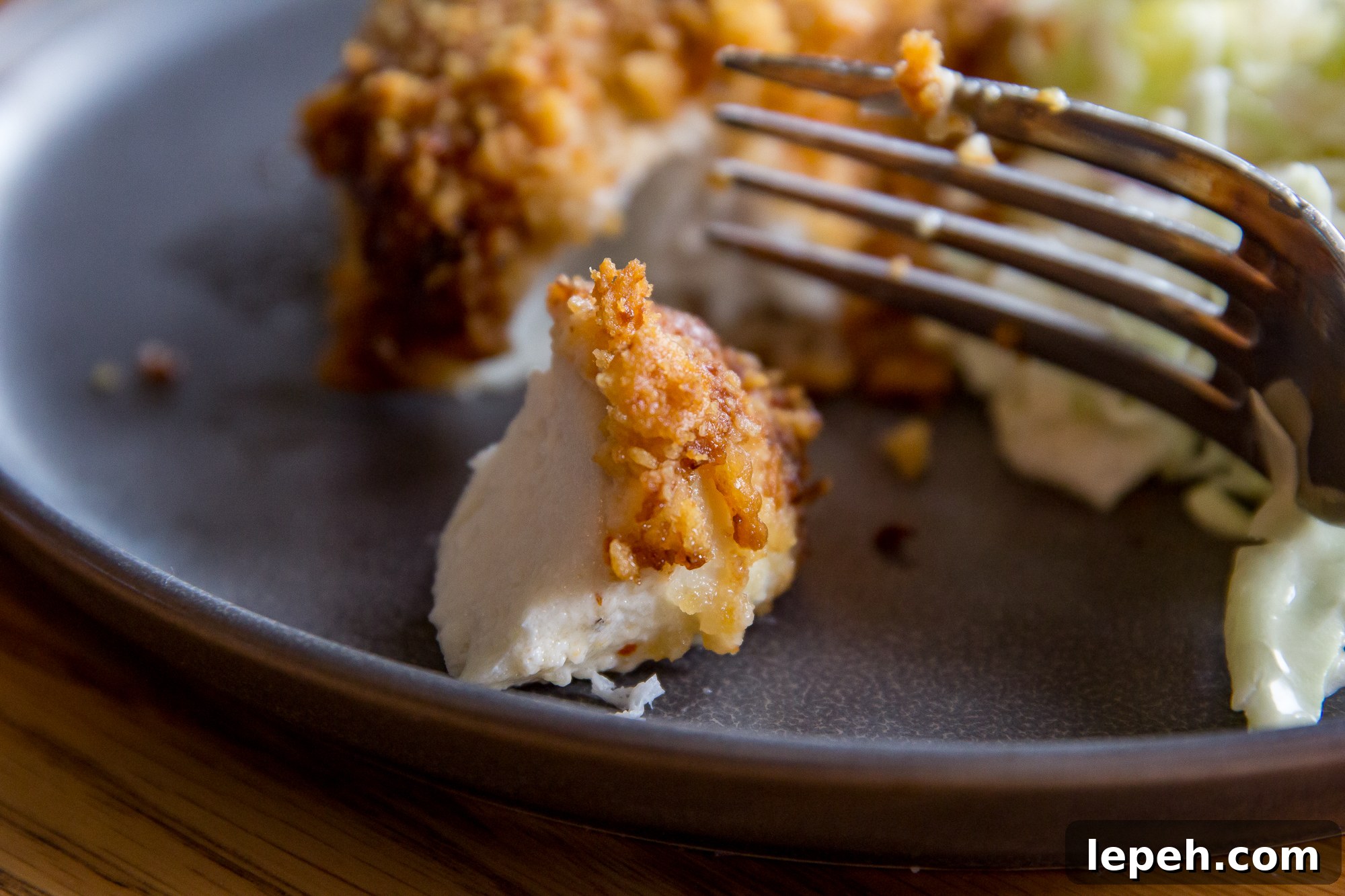 Air Fryer Parmesan Crusted Halibut on a gray plate being cut into with a fork.