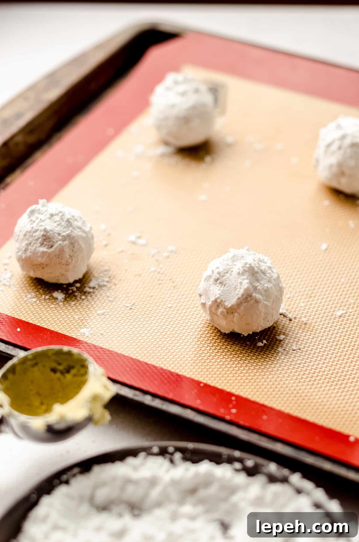 lemon crinkle cookie dough balls coated in powdered sugar on a baking sheet