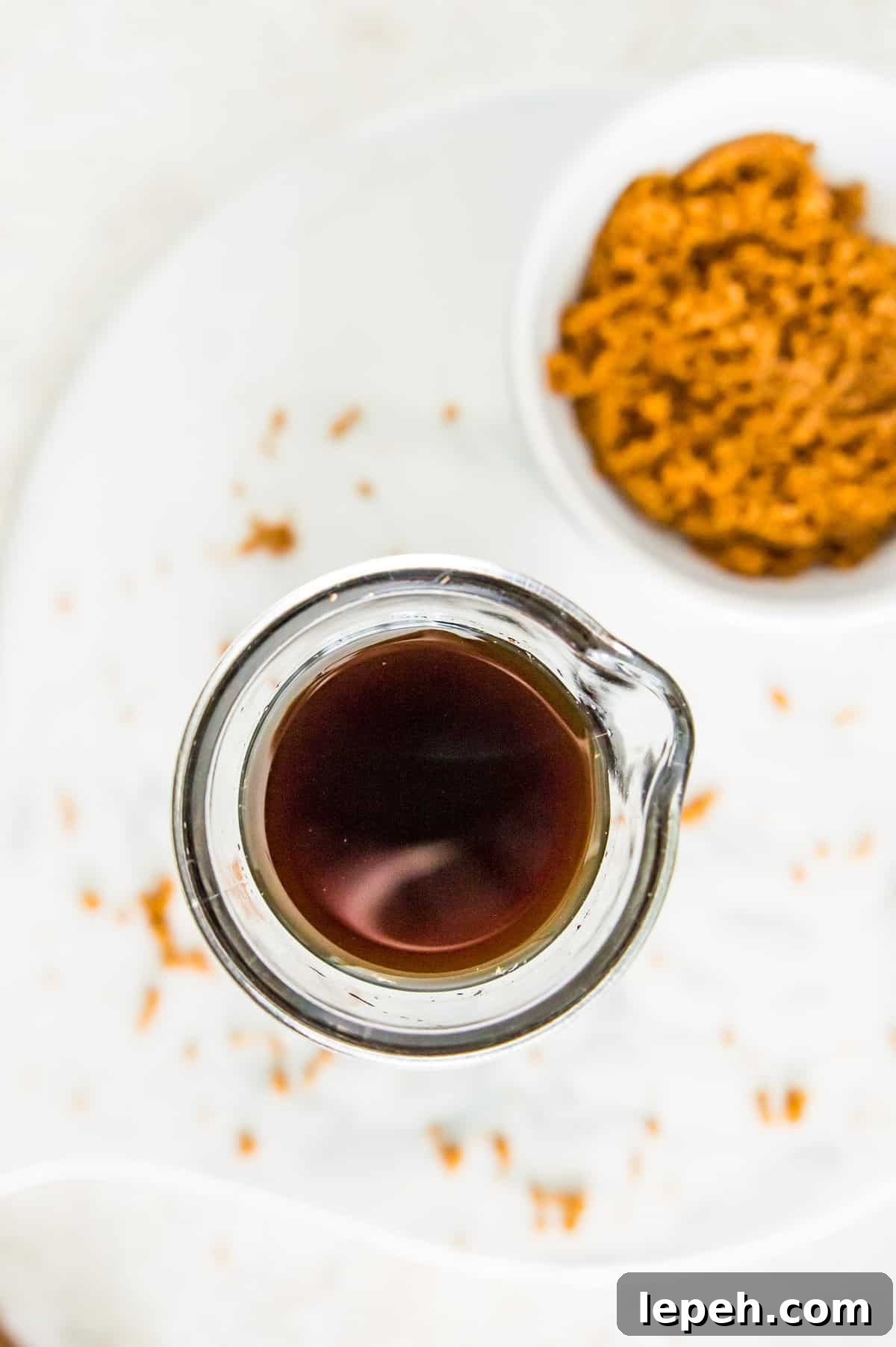 A glass bottle full of brown sugar simple syrup with a bowl of brown sugar next to it.