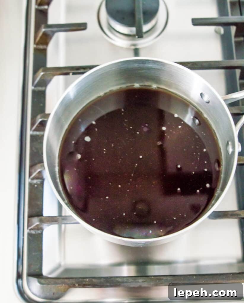 A saucepan on a stovetop with melted brown sugar in it.