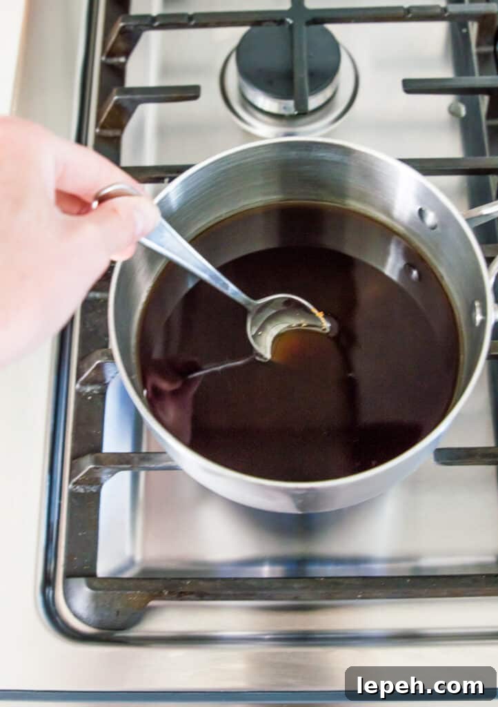 Brown sugar syrup in a pot on the stovetop being stirred with a spoon.