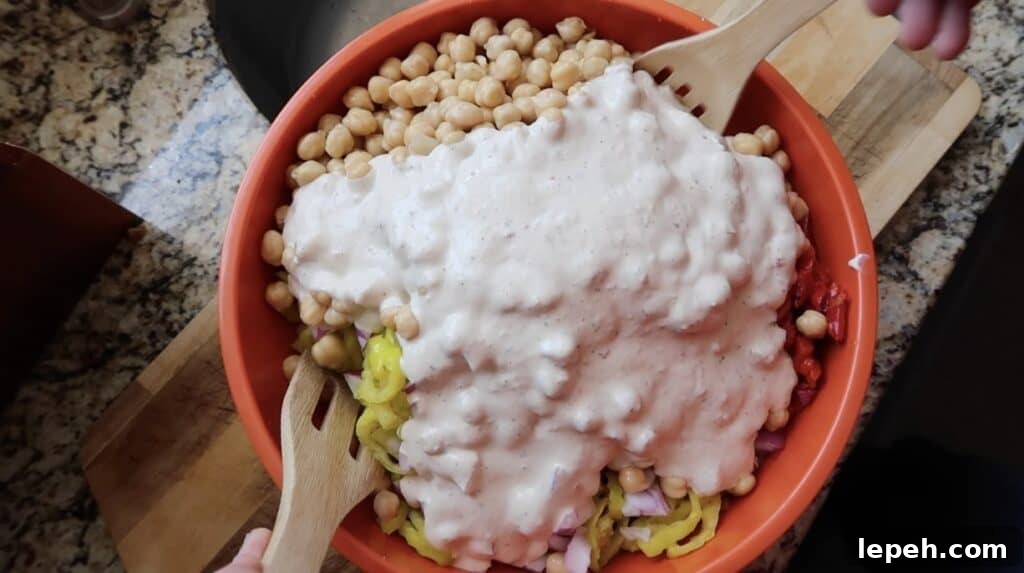 Adding creamy Italian salad dressing to the bowl of pasta.