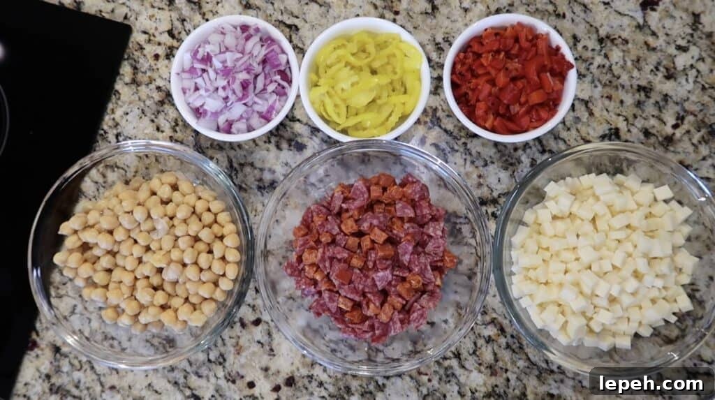 Bowls featuring diced red onion, sliced banana peppers, roasted red peppers, diced provolone, diced charcuterie meat (such as salami, soppressata, and/or pepperoni), and chickpeas.