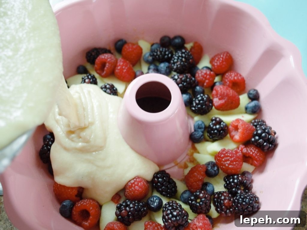 Berry & apple Upside down bundt cake pouring batter over berries 