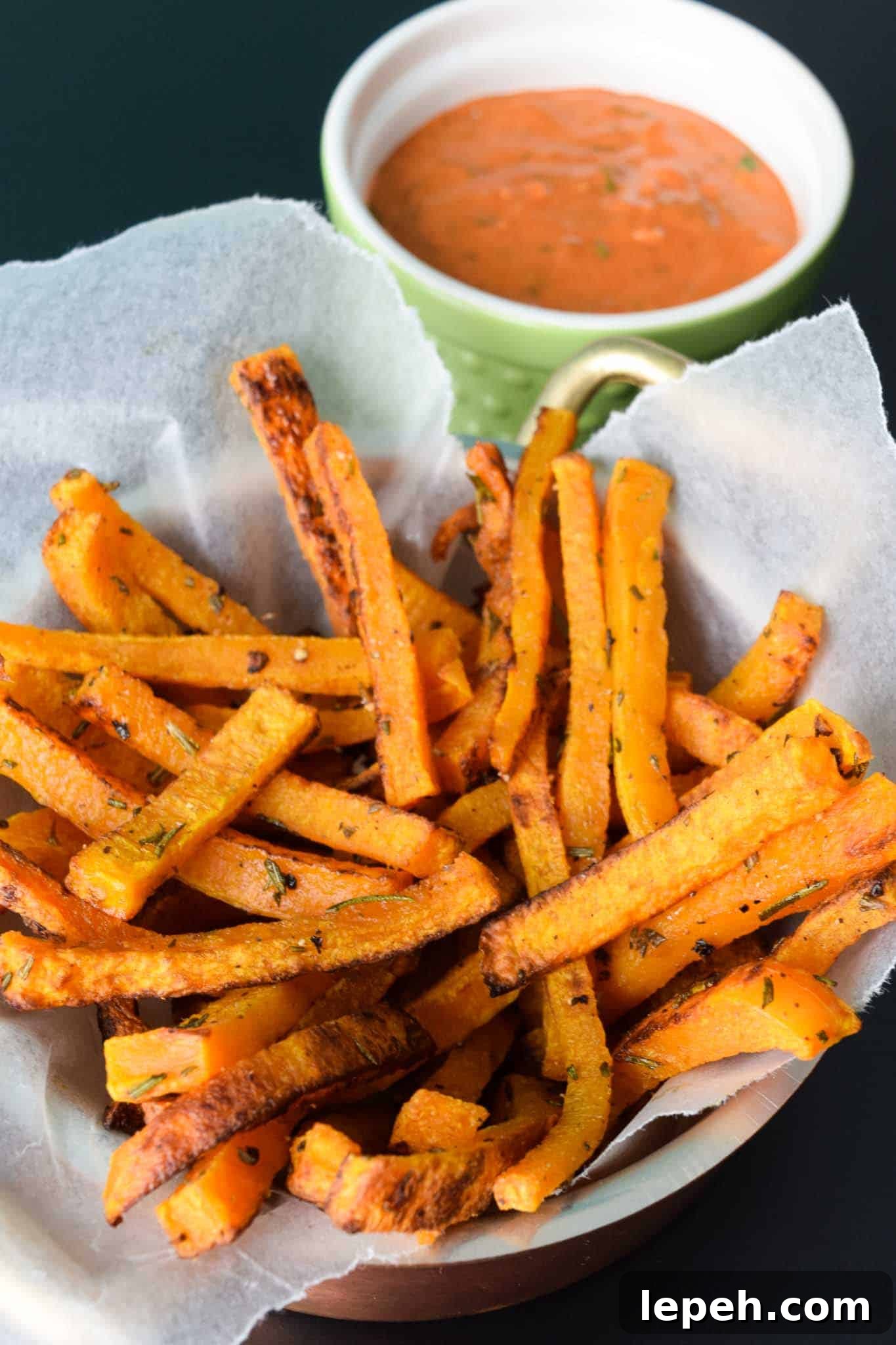 Butternut Squash Fries in waxed paper lined bowl with magic sauce in green bowl behind 