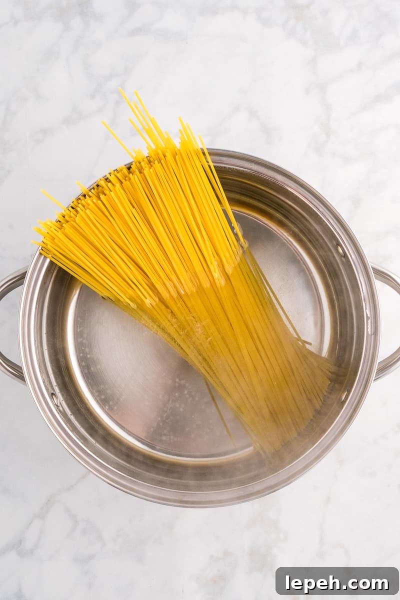Spaghetti noodles in pot with boiling water.